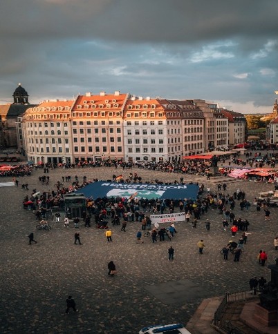 Crowded square with people and large building.